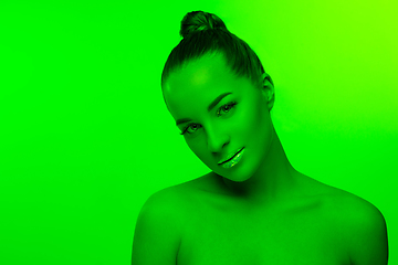 Image showing Handsome woman\'s portrait isolated on green studio background in neon light, monochrome