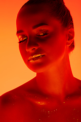 Image showing Handsome woman\'s portrait isolated on orange gradient studio background in neon light, monochrome