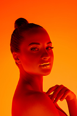 Image showing Handsome woman\'s portrait isolated on orange gradient studio background in neon light, monochrome