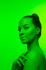 Image showing Handsome woman\'s portrait isolated on green studio background in neon light, monochrome