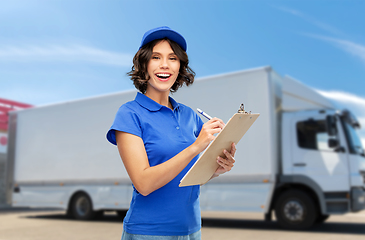 Image showing happy delivery girl with clipboard and pen writing