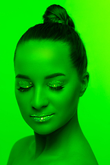 Image showing Handsome woman\'s portrait isolated on green studio background in neon light, monochrome