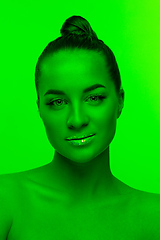 Image showing Handsome woman\'s portrait isolated on green studio background in neon light, monochrome