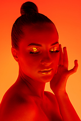 Image showing Handsome woman\'s portrait isolated on orange gradient studio background in neon light, monochrome