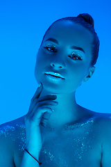 Image showing Handsome woman\'s portrait isolated on blue studio background in neon light, monochrome