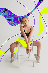 Image showing Stylish young girl\'s portrait on white studio background with bright illustrated lines of fluid neoned colors. Having fun, happy, full length