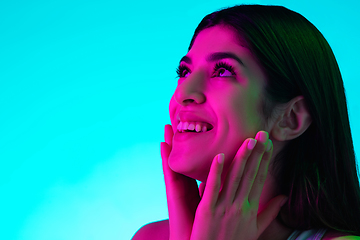 Image showing Brunette beautiful woman\'s portrait isolated on blue studio background in multicolored neon light