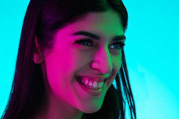 Image showing Brunette beautiful woman\'s portrait isolated on blue studio background in multicolored neon light