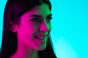 Image showing Brunette beautiful woman\'s portrait isolated on blue studio background in multicolored neon light