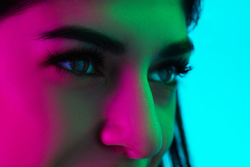 Image showing Close up beautiful woman\'s eyes isolated on blue studio background in multicolored neon light