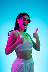 Image showing Brunette beautiful woman\'s portrait isolated on blue studio background in multicolored neon light