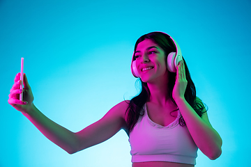 Image showing Brunette beautiful woman\'s portrait isolated on blue studio background in multicolored neon light