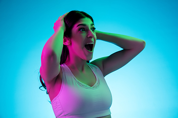 Image showing Brunette beautiful woman\'s portrait isolated on blue studio background in multicolored neon light