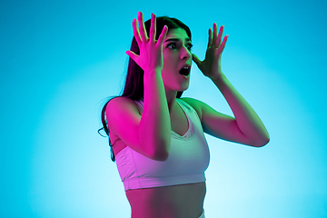 Image showing Brunette beautiful woman\'s portrait isolated on blue studio background in multicolored neon light