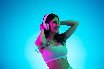 Image showing Brunette beautiful woman\'s portrait isolated on blue studio background in multicolored neon light