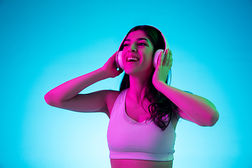 Image showing Brunette beautiful woman\'s portrait isolated on blue studio background in multicolored neon light