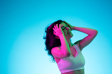 Image showing Brunette beautiful woman\'s portrait isolated on blue studio background in multicolored neon light