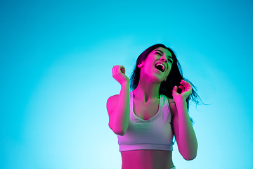 Image showing Brunette beautiful woman\'s portrait isolated on blue studio background in multicolored neon light