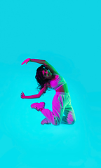 Image showing Brunette beautiful woman\'s portrait isolated on blue studio background in multicolored neon light. Jumping high. flying