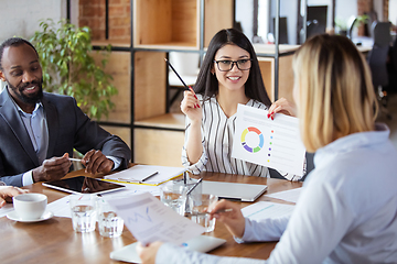 Image showing Diverse group of co-workers having casual discussion in office. Executives during friendly discussion, month reporting, creative meeting