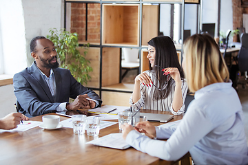 Image showing Diverse group of co-workers having casual discussion in office. Executives during friendly discussion, month reporting, creative meeting