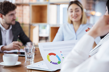 Image showing Diverse group of co-workers having casual discussion in office. Executives during friendly discussion, month reporting, creative meeting. Focused on graphs.