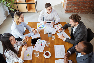 Image showing Diverse group of co-workers having casual discussion in office. Executives during friendly discussion, month reporting, creative meeting. Top view.