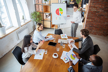 Image showing Diverse group of co-workers having casual discussion in office. Executives during friendly discussion, month reporting, creative meeting. Top view.