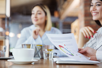 Image showing Diverse group of co-workers having casual discussion in office. Executives during friendly discussion, month reporting, creative meeting. Focus on graphs.