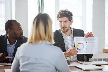 Image showing Diverse group of co-workers having casual discussion in office. Executives during friendly discussion, month reporting, creative meeting