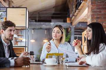 Image showing Diverse group of co-workers having casual discussion in office. Executives during friendly discussion, month reporting, creative meeting