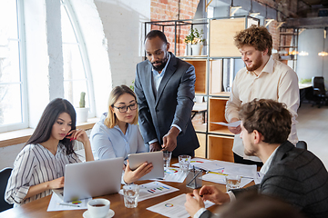 Image showing Diverse group of co-workers having casual discussion in office. Executives during friendly discussion, month reporting, creative meeting