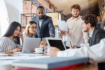 Image showing Diverse group of co-workers having casual discussion in office. Executives during friendly discussion, month reporting, creative meeting