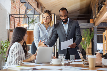 Image showing Diverse group of co-workers having casual discussion in office. Executives during friendly discussion, month reporting, creative meeting