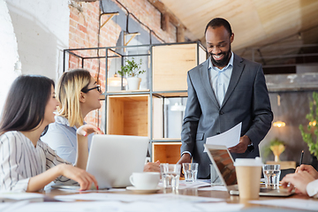 Image showing Diverse group of co-workers having casual discussion in office. Executives during friendly discussion, month reporting, creative meeting