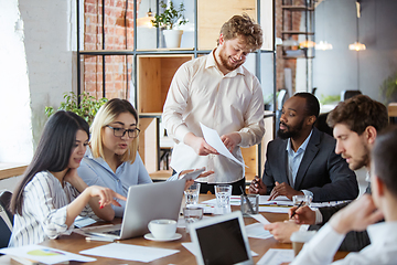 Image showing Diverse group of co-workers having casual discussion in office. Executives during friendly discussion, month reporting, creative meeting