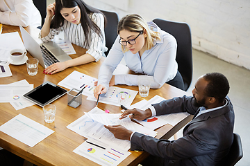 Image showing Diverse group of co-workers having casual discussion in office. Executives during friendly discussion, month reporting, creative meeting. Top view.