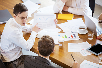 Image showing Diverse group of co-workers having casual discussion in office. Executives during friendly discussion, month reporting, creative meeting. Top view.