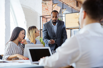 Image showing Diverse group of co-workers having casual discussion in office. Executives during friendly discussion, month reporting, creative meeting