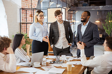 Image showing Diverse group of co-workers having casual discussion in office. Executives during friendly discussion, month reporting, creative meeting