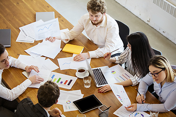 Image showing Diverse group of co-workers having casual discussion in office. Executives during friendly discussion, month reporting, creative meeting. Top view.