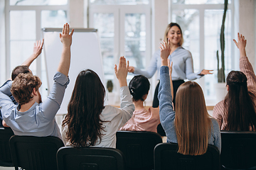 Image showing Female speaker giving presentation in hall at workshop. Audience or conference hall. Rear view of unrecognized participants.