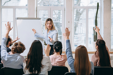 Image showing Female speaker giving presentation in hall at workshop. Audience or conference hall. Rear view of unrecognized participants.