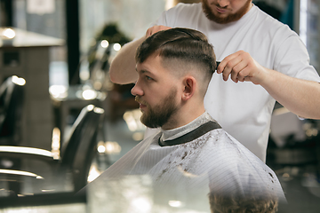 Image showing Close up master barber, stylist does the hairstyle to guy, young man. Professional occupation, male beauty concept