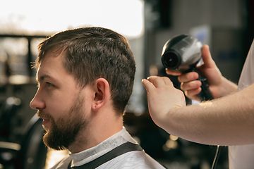 Image showing Close up of client of master barber, stylist during getting care of hairstyle. Professional occupation, male beauty concept