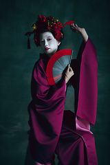 Image showing Young japanese woman as geisha on dark green background. Retro style, comparison of eras concept.