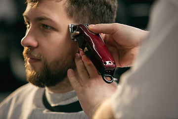 Image showing Close up of client of master barber, stylist during getting care of hairstyle. Professional occupation, male beauty concept