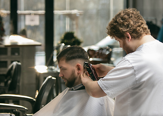 Image showing Close up master barber, stylist does the hairstyle to guy, young man. Professional occupation, male beauty concept