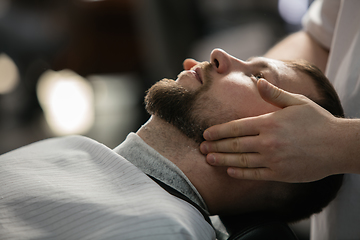 Image showing Close up of client of master barber, stylist during getting care of mustache and beard. Professional occupation, male beauty concept