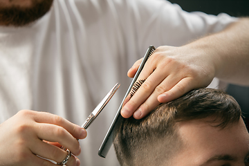 Image showing Close up hands of master barber, stylist does the hairstyle to guy, young man. Professional occupation, male beauty concept